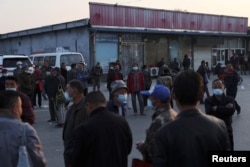 农民工和打日结零工的人聚集在北京郊区的一条街道上等着“趴活儿”。(2022年4月20日)