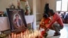 FILE - Mourners place candles in a room of Radio Amplitude FM where a portrait of journalist Martinez Zogo has been placed to pay tribute to him, in the Elig Essono district in Yaounde, Jan. 23, 2023. 