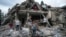 FILE - Palestinians look at the destruction after an Israeli airstrike in Deir al Balah, Gaza Strip, April 30, 2024.