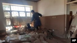 An Afghan man collects his belongings from his damaged home after heavy flooding in Baghlan province, in northern Afghanistan, May 12, 2024.