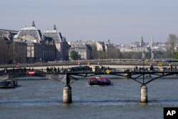 FILE - Barges travel along the River Seine in Paris, Wednesday, April 5, 2023. (AP Photo/Christophe Ena)