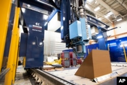 A section of wall of a house is being printed on a 3D printer at the University of Maine on Oct. 12, 2023, in Orono, Maine. An even larger printer unveiled on Tuesday, April 23, 2024, may one day create entire neighborhoods. (AP Photo/Kevin Bennett)