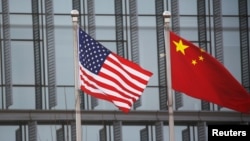বেইজিংয়ে একটি আমেরিকান কোম্পানির ভবনের বাইরে চীন ও আমেরিকার পতাকা উড়ছে। ছবিঃ ২১ জানুয়ারী, ২০২১ 