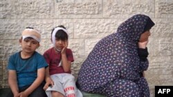 ইসরায়েলি বোমা হামলায় নিহত স্বজনদের মৃতদেহ শনাক্ত করতে গাজার দেইর আল-বালাহ'র আল-আকসা শহীদ হাসপাতালের আঙিনায় আহত ফিলিস্তিনি ছেলেরা তাদের পরিবার নিয়ে অপেক্ষা করছে। (১১ মে, ২০২৪) 