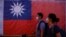 台北街头民众走过竖立的台湾旗帜。（2023年8月18日）