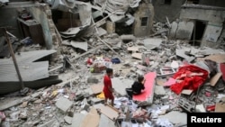 গাজা ভূখন্ডের দক্ষিণাঞ্চলে, রাফায় ইসরায়েল ও ফিলিস্তিনি ইসলামপন্থি গোষ্ঠী হামাসের মধ্যে চলমান সংঘাতের সময়ে ফিলিস্তিনি শিশুরা ইসারায়েলের হামলায় বিধ্বস্ত একটি বাড়ির সামনে তল্লাশি করছে। এপ্রিল২৭, ২০২৪।
