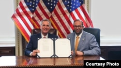美国国会众议院议长凯文·麦卡锡(左)拿着他已签字的《美台21世纪贸易倡议首批协定实施法》与众议院筹款委员会主席杰森·史密斯众议员合影。(众议员杰森··史密斯办公室提供）