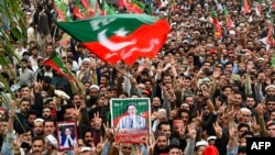 Pakistan Tehreek-e-Insaf (PTI) party supporters hold portraits of former prime minister Imran Khan, as they protest against the alleged skewing in country's national election, in Peshawar, March 10, 2024. 
