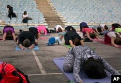 FILE - Seorang bayi berjalan-jalan di sekitar siswa yang tengah mengikuti kelas yoga luar ruangan di Taman Nasional Germia di ibu kota Kosovo Pristina, 16 Juni 2016. (AP/Visar Kryeziu)