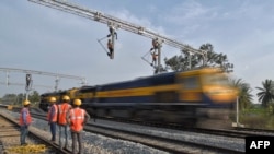 印度铁路公司的合同工在班加罗尔郊区架设用于在铁轨上牵引电缆线供机车使用的设施。（资料照片，2021年1月15 日）