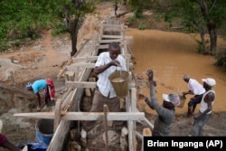 Residents in Machakos County, Kenya, build a sand dam on Thursday, Feb. 29, 2024. Sand dam helps minimize water loss through evaporation and recharges groundwater. (AP Photo/Brian Inganga)