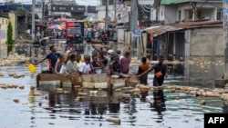 Warga menyeberangi banjir di distrik Pompage di Kinshasa, Republik Demokratik Kongo, pada 9 Januari 2024. (Foto: AFP)