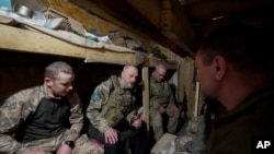 资料照片：一名随军神职人员在东正教复活节前夜在哈尔科夫州前线附近的掩体内与乌军士兵交谈。(2023年4月15日)