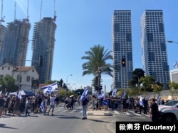10月14日从早上开始在特拉维夫市中心的国防部大楼旁的街道上聚集的群众，原本是为被哈马斯挟持的人质声援并支持人质家属的守夜抗议行动、下午分成为两阵营，街道左边强调声援人质，街道右边演变为对政府不满的抗议。(美国之音 赖素芬)