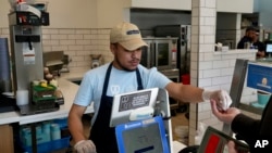 An employee collects payment at an Auntie Anne's and Cinnabon store in Livermore, Calif., March 28, 2024.