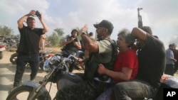 2023年10月7日，一名被俘的以色列平民（中，穿红衣的女士）被从卡法阿扎基布兹运送到加沙地带。(AP Photo/Hatem Ali)