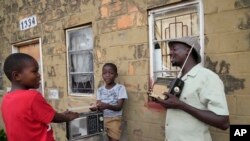 Ngwiza Khumbulani Moyo, a vintage collector, shows young boys some of his old radio sets outside his home in Bulawayo, Zimbabwe, Feb. 15, 2023.