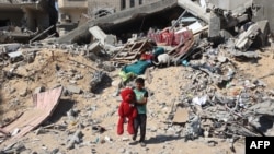 2024年6月21日，以色列轰炸汗尤尼斯后，一名巴勒斯坦儿童手拿从被毁建筑物的废墟中找回的毛绒熊。(法新社照片)