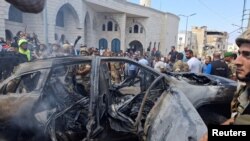 据两名巴勒斯坦消息人士称，2024年8月21日的黎巴嫩，在以色列袭击南部港口城市西顿郊区后，人们和黎巴嫩军人站在一辆被烧毁的汽车附近。(路透社照片)