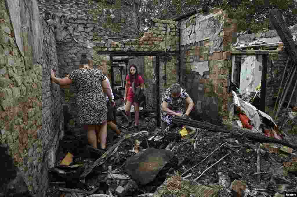 Local residents collect things in their destroyed building hit by a Russian missile strike in Zaporizhzhia, Ukraine, Aug. 27, 2024.