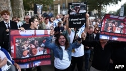 民众手举被巴勒斯坦武装分子劫为人质的以色列妇女和儿童的照片在伦敦的英国首相官邸唐宁街10号外举行集会。（2023年10月9日）