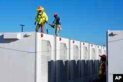FILE - Workers do checks on battery storage pods at Orsted's Eleven Mile Solar Center lithium-ion battery storage energy facility Thursday, Feb. 29, 2024, in Coolidge, Ariz. (AP Photo/Ross D. Franklin)