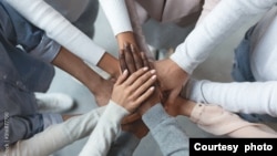 FILE - Business team putting hands together on top of each other. (Prostock-studio via Adobe Stock)