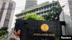 ঢাকার মতিঝিলে বাংলাদেশ ব্যাঙ্কের দফতরের পাশ দিয়ে একজন নারী হেঁটে যাচ্ছেন। ফাইল ফটোঃ ১৯ জুলাই, ২০২৩।