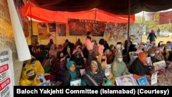 
د کراچۍ په مظاهره کې د لفټ ډيموکريټک فرنټ تنظيم غړو په اسلام اباد کې د بلوڅ یکجهتي کونسل پرلت سره د يوالي اظهار هم وکړو. په دې تصویر کې د بلوچ یکجهتي کونسل فعالان لیدل کېږي چې په اسلام اباد کې د خلکو د بې درکیو په ضد په پرلت ناست دي
