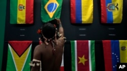 一名土著男子在巴西贝伦举行的亚马逊合作会议上观看巴西国旗。（2023年8月6日）
