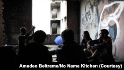 中国移民在波斯尼亚比哈奇的一栋废弃建筑中与人道组织“无名厨房”的志愿者交谈。