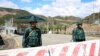 FILE - Men guard an Azerbaijani checkpoint set up at the entry of the Lachin Corridor, the Armenian-populated breakaway Nagorno-Karabakh region's only land link with Armenia, by a bridge across the Hakari river, on May 2, 2023. 