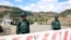 FILE - Men guard an Azerbaijani checkpoint set up at the entry of the Lachin Corridor, the Armenian-populated breakaway Nagorno-Karabakh region's only land link with Armenia, by a bridge across the Hakari river, on May 2, 2023. 