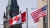FILE - The Canadian and US flags are displayed on lampposts March 22, 2023, near Parliament Hill in Ottawa, Ontario. 