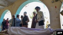 Relatives stand around the body of a victim of a suicide bomb attack during a funeral ceremony at a mosque in Kandahar on March 21, 2024. 