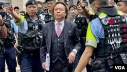 香港民主派初選47人案其一名獲判無罪的被告，大律師劉偉聰5月30日手持厚達337頁的判辭離開西九龍裁判法院時，被大批軍裝警員包圍。(美國之音)