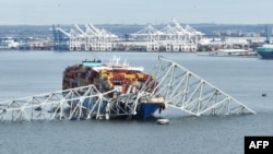 In this aerial image, the steel frame of the Francis Scott Key Bridge sits on top of a container ship after the bridge collapsed, in Baltimore, Maryland, on March 26, 2024. (Photo by Jim WATSON / AFP)