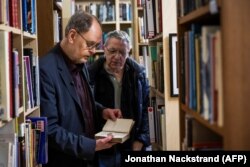 Arsiparis Clas Svahn (Kiri) dan Anders Liljegren membuka buku di Archives for the Unexplained (AFU) di Norrkoping, Swedia pada 12 Maret 2024. (Foto: Jonathan Nackstrand/AFP)