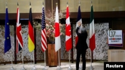 资料照：一名男子在日本东京举行七国集团外交部长会议期间整理成员的旗帜。（2023年11月8日）