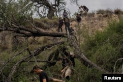 一组来自中国的移民渡过美墨边境的格兰德河走出美国德克萨斯州的丛林，他们寻找美国执法人员以便进入移民程序。（2023年4月4日）