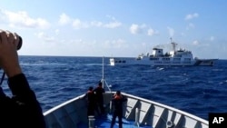 资料照：菲律宾海岸警卫队发布照片显示，一艘中国海警船（上）正在有争议的南中国海阻拦一艘菲律宾政府船只登陆铁线礁（Sandy Cay ）。（2024年3月21日）