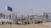 FILE - Pakistani and Taliban flags flutter on their respective sides while people walk through a security barrier to cross the Pakistan-Afghan border in Chaman, Pakistan, Aug. 18, 2021.