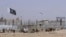 FILE - Pakistani and Taliban flags flutter on their respective sides while people walk through a security barrier to cross the Pakistan-Afghan border in Chaman, Pakistan, Aug. 18, 2021.