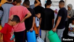 资料照片：在加沙地带南部汗尤尼斯，一些巴勒斯坦人在饮用水短缺的情况下聚集取水。（2023年10月15日）