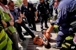 A University of Southern California protester is detained by USC Department of Public Safety officers during a pro-Palestinian occupation at the campus' Alumni Park on Wednesday, April 24, 2024 in Los Angeles. (AP Photo/Richard Vogel)