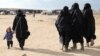 Seorang perempuan menuntun anak kecil ketika berjalan di kamp al-Hol, Suriah, pada 8 Januari 2020. (Foto: Reuters/Goran Tomasevic)