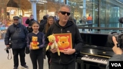 1月26日，在伦敦圣潘克拉斯国际车站，钢琴家卡瓦纳展示维尼熊玩偶和画像 (美国之音/李伯安)