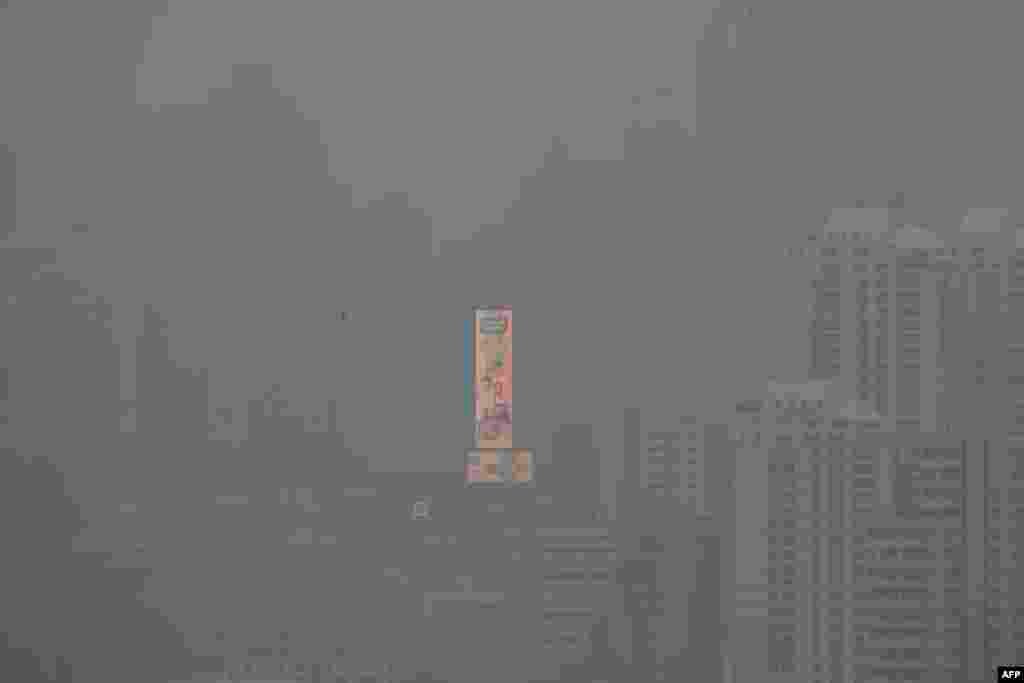 A large illuminated advertisement on the side of a building is pictured amid high levels of air pollution in Bangkok, Thailand. (Photo by Alex OGLE / AFP)