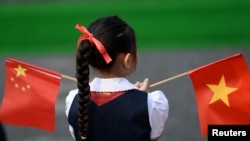 资料照：：一个越南小女孩在河内的越南国会大厦前手持中越两国国旗。（2017年11月12日）