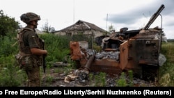 Украинский военнослужащий стоит рядом с уничтоженной российской БМП-3 в недавно освобожденном селе Благодатное в Донецкой области, Украина, 17 июня 2023 года